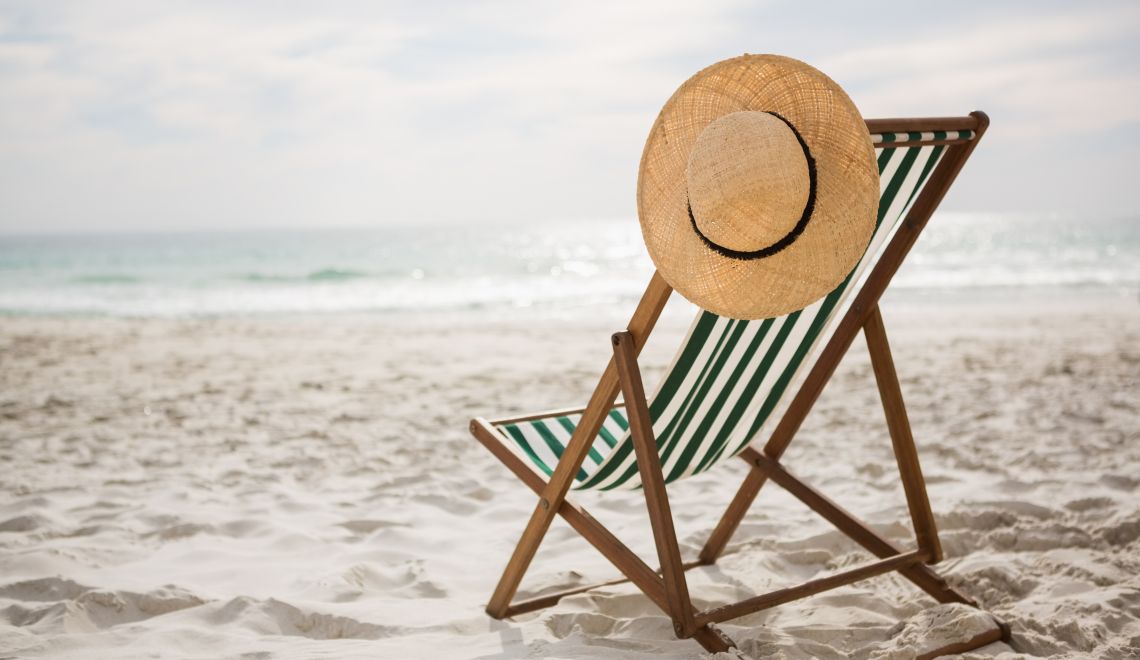 Straw hat kept on empty beach chair
